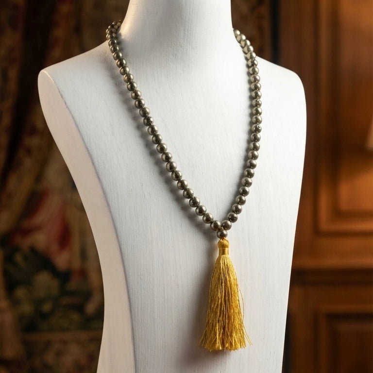 Necklace with a yellow tassel on a mannequin against a wooden panel background